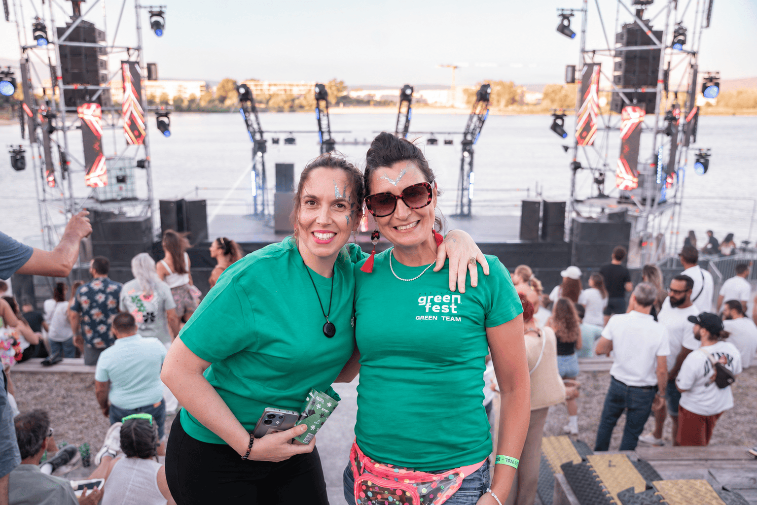 Deux bénévoles de la Green Team souriantes devant la scène et le lac de Monteux